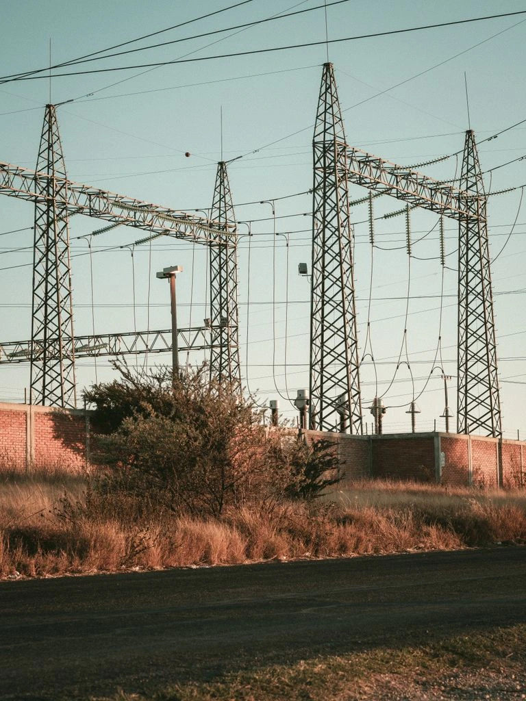Subestación de transmisión eléctrica en los Andes colombianos, con dos ingenieros revisando paneles de control.